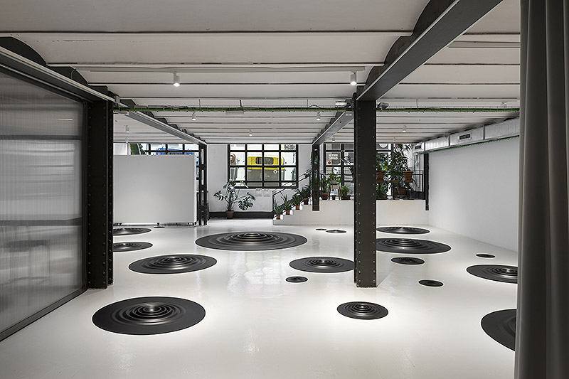 Fluctus Lacus, Carmen Ortíz - instalación artística de piezas circulares de caucho negro con forma de ondulaciones circulares colocadas en el suelo de una galería de arte