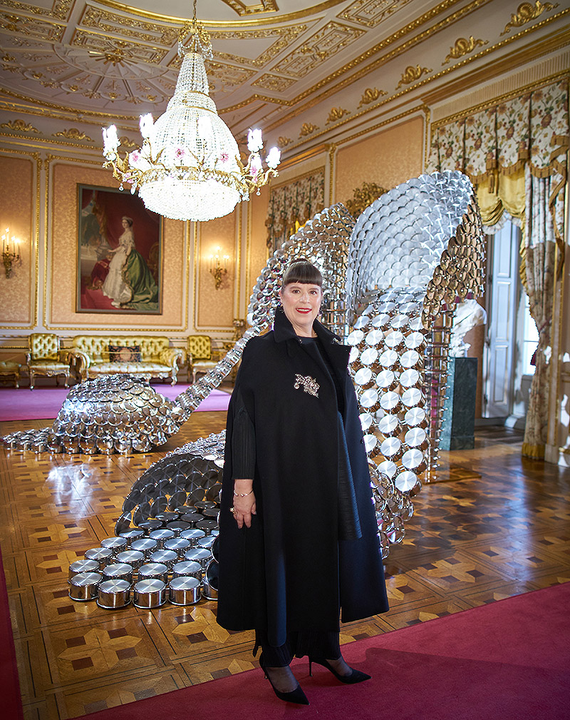 Imagen de la artista con un zapato de tacón gigante detrás