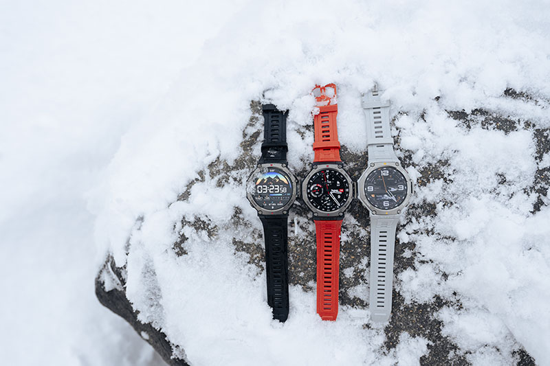 Tres modelos del Amazfit T-Rex 3 (negro, naranja y gris) sobre una superficie nevada