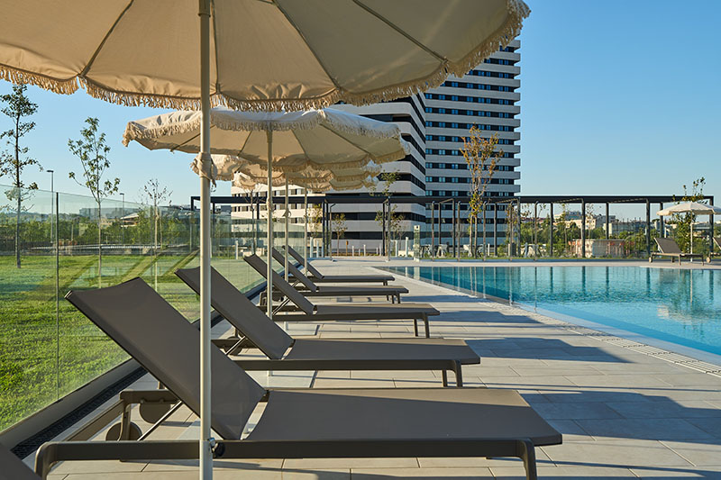 Be Casa Alcobendas: zona de sombrillas y hamacas en la piscina exterior de Be Casa Alcobendas.