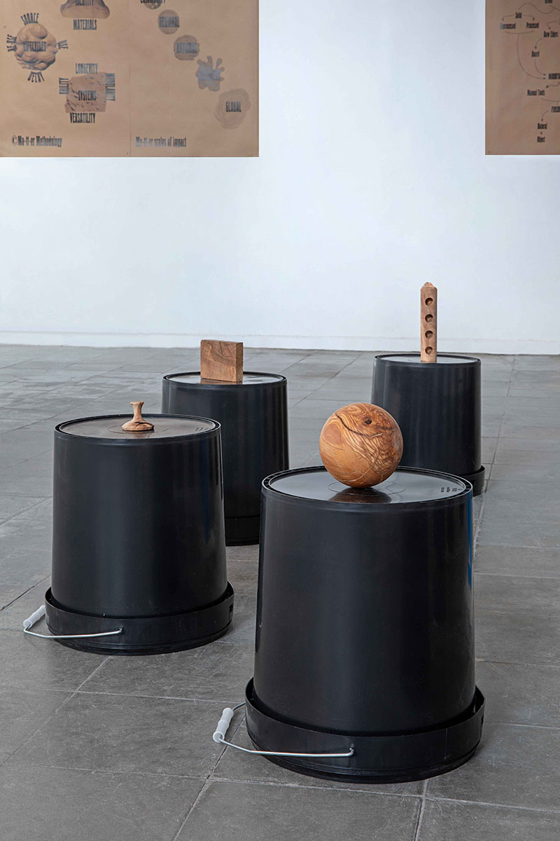 En la exposición Uprooted de Jorge Penadés en el Madrid Design Festival, varias formas geométricas talladas en madera de raíz de olivo reposan sobre cubos negros