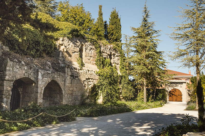 Quinta San Francisco: Restos de antiguas construcciones de piedra cubiertas de vegetación junto a un camino arbolado, integradas en el entorno del hotel