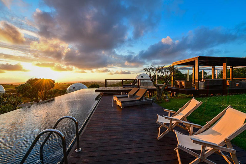 Piscina infinity con tumbonas y vistas al atardecer en Wecamp Reserva Alecrim