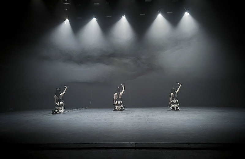 Models. Lee Gamble y Candela Capitán. imagen de performance se ve a 3 chicas iluminadas y sujetas por cadenas