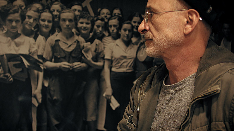 Santiago Sierra: El Dedo en la Llaga - fotograma del documental, se ve al artista mirando una foto