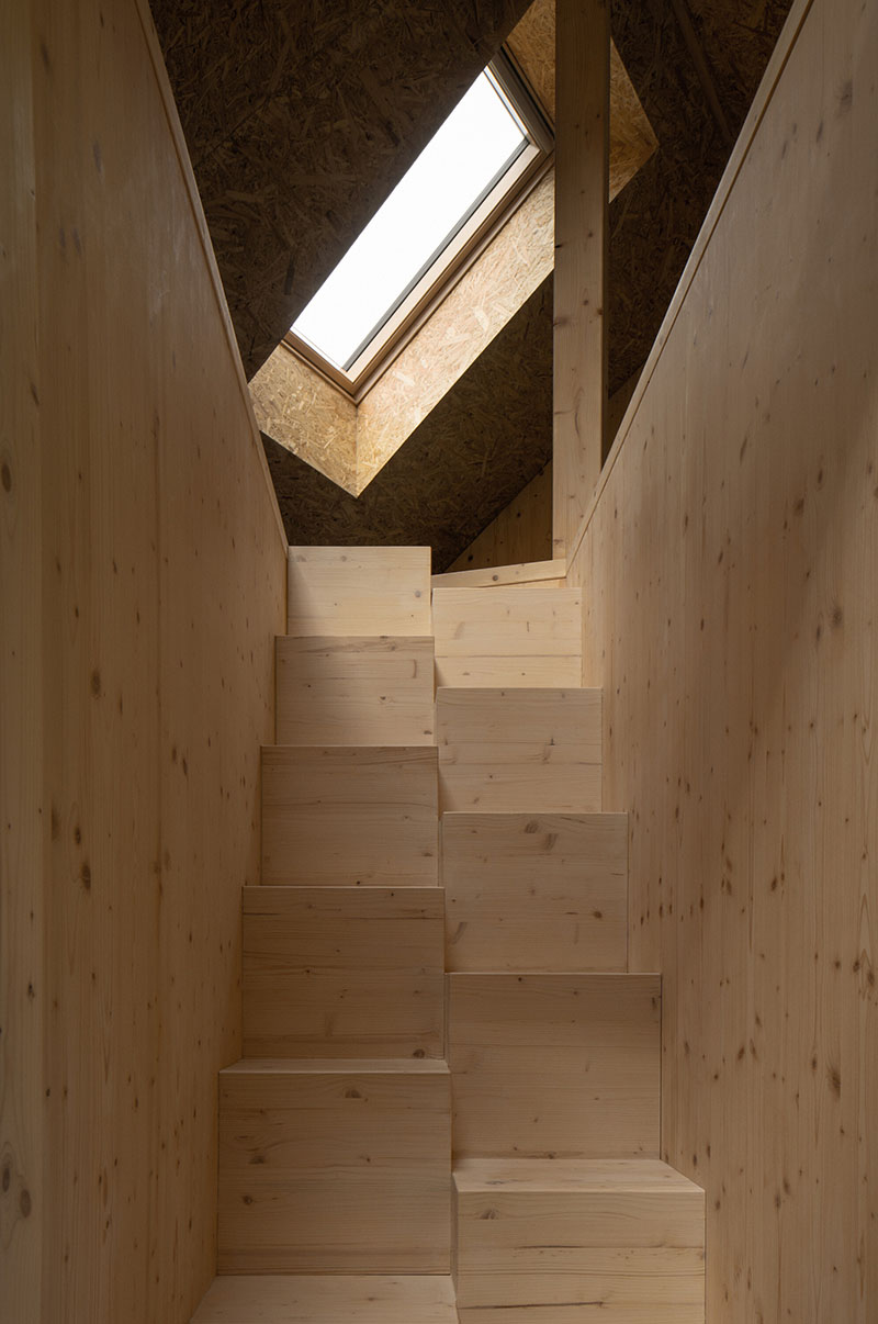 Casa de Campo de New How Architects: escalera de madera iluminada por un tragaluz inclinado