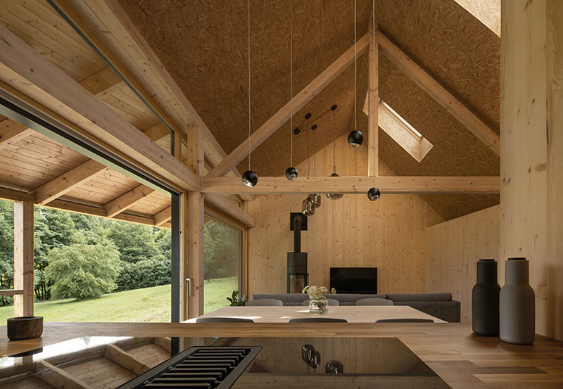 Casa de Campo de New How Architects: cocina abierta al salón con acabados en madera y negro mate