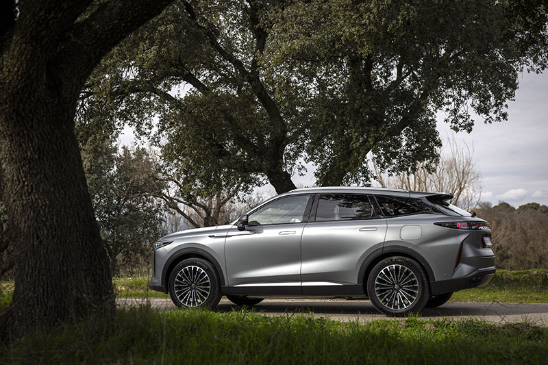 Omoda 9 SHS, de Chery, en una carretera rodeada de árboles visto desde un lateral.